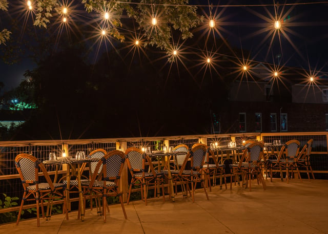 The upper patio at Concordance Ferments at night, bistro chairs under strings of warm lights