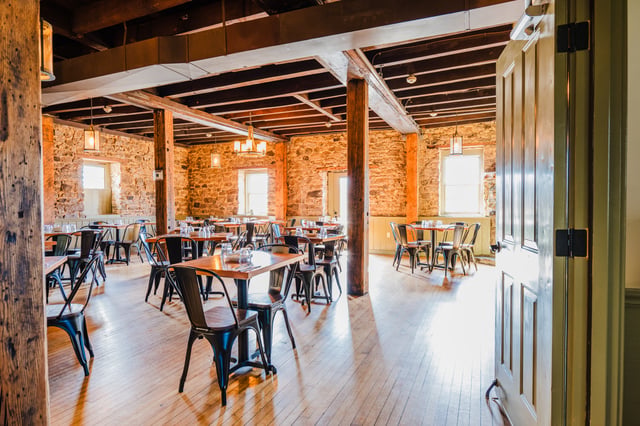 The dining room at Concordance Ferments — stone walls, timber posts and wood tables