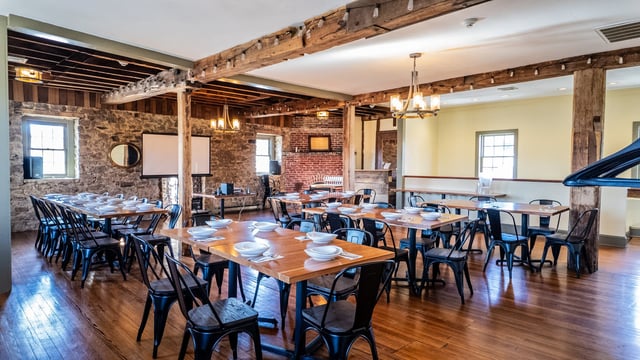 The third-floor private event space at Concordance Ferments set for a seated dinner for up to 60 guests, with exposed beams and stone walls